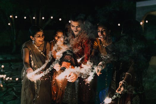 Group of South Asian adults celebrating Diwali with sparklers at night in traditional clothing.