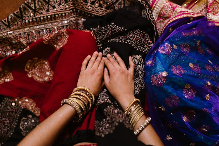 Person Wearing Gold Bangles Holding Textiles