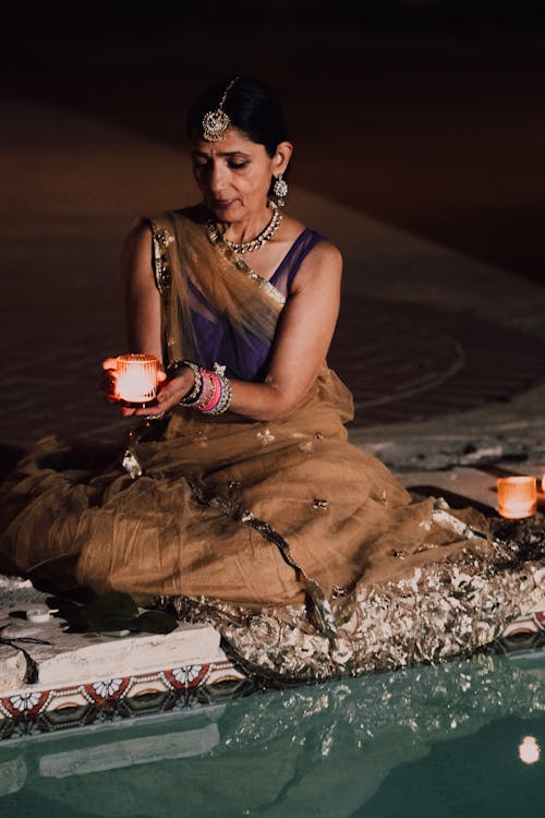 Woman in Traditional Dress Holding a Lighted Candle