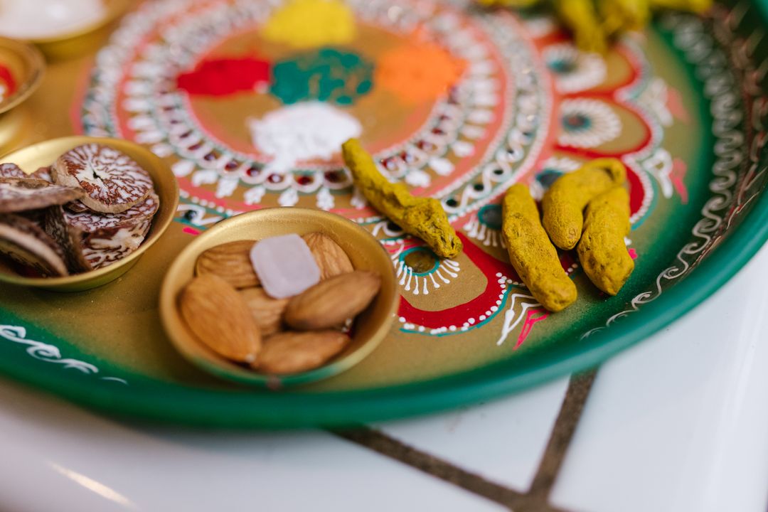 Raksha Bandhan Food Traditions in India: What Goes on the Plate and Why 1 Close-up of a traditional Raksha Bandhan thali showing kumkum, diya, rice grains, rakhi, and a small piece of mohanthal