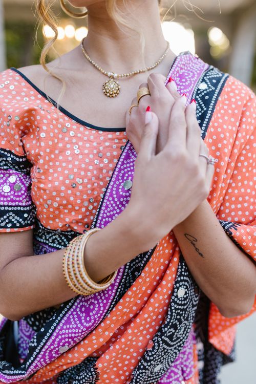 Free Detailed view of hands adorned with jewelry wearing a vibrant traditional sari. Stock Photo