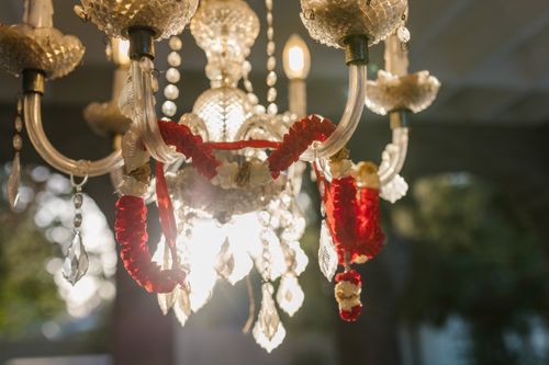 Free A beautifully illuminated crystal chandelier adorned with vibrant red and white floral garlands. Stock Photo