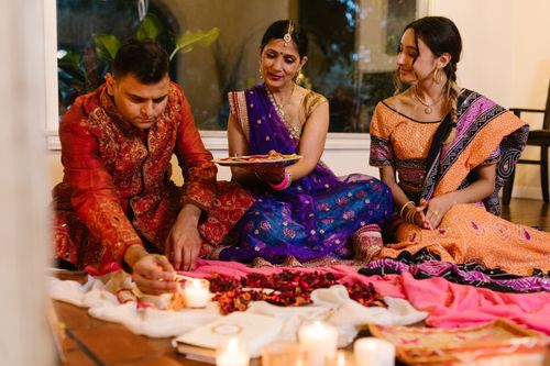 Free Three individuals celebrate Diwali with candles and traditional attire indoors. Stock Photo