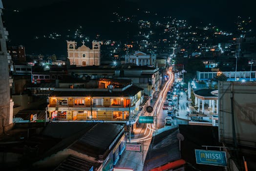 A lively night cityscape featuring bustling streets with illuminated buildings and a historic church in the background.
