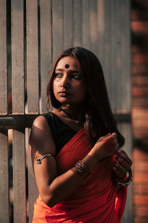 Free A woman in vibrant traditional attire poses against a fence, captured in Dhaka, Bangladesh. Stock Photo