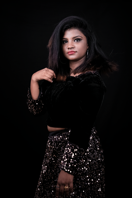 Free Stylish woman posing confidently in a sparkling sequin outfit during a studio photoshoot. Stock Photo