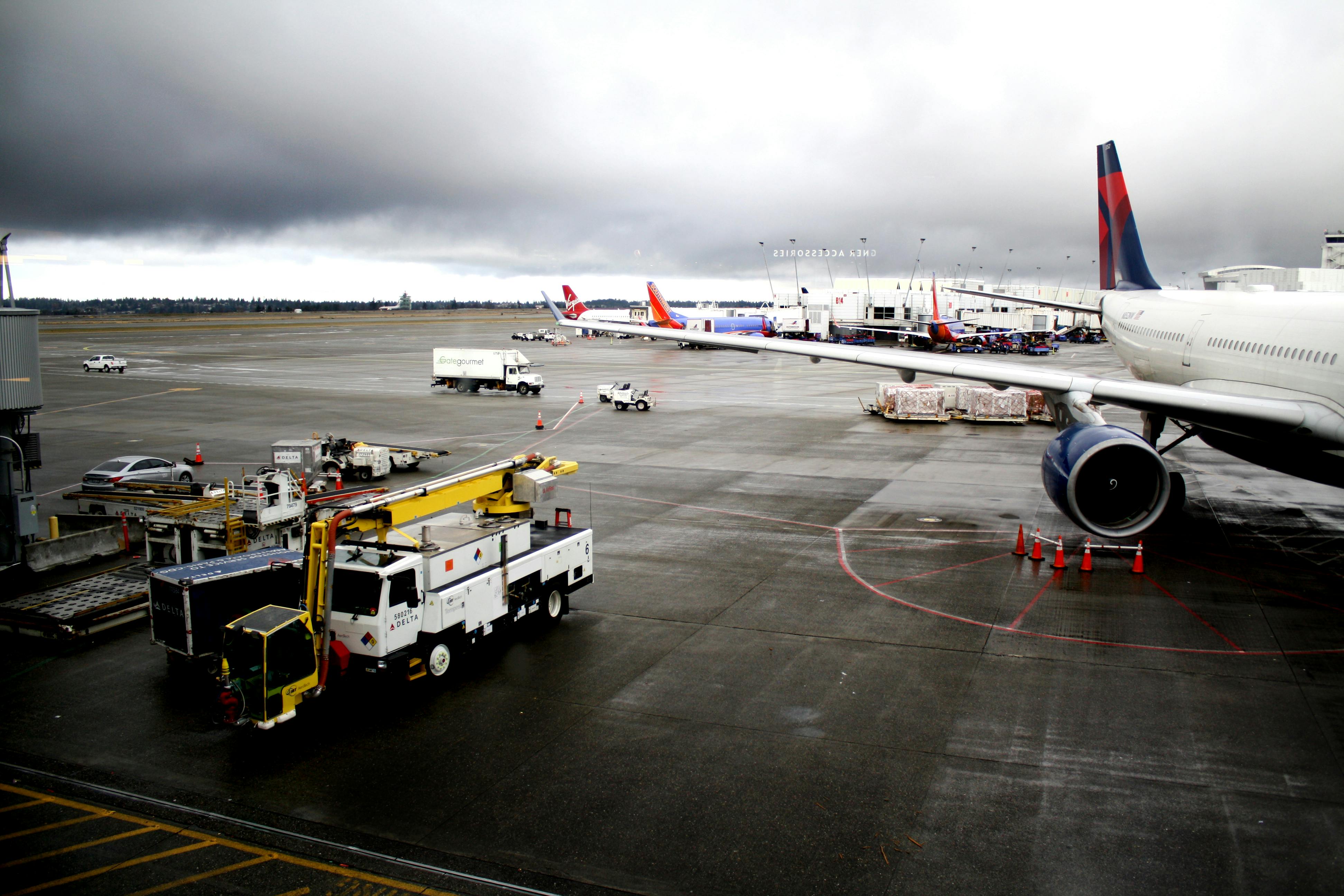 Free View of airport tarmac with multiple airplanes and ground service equipment under cloudy skies. Stock Photo