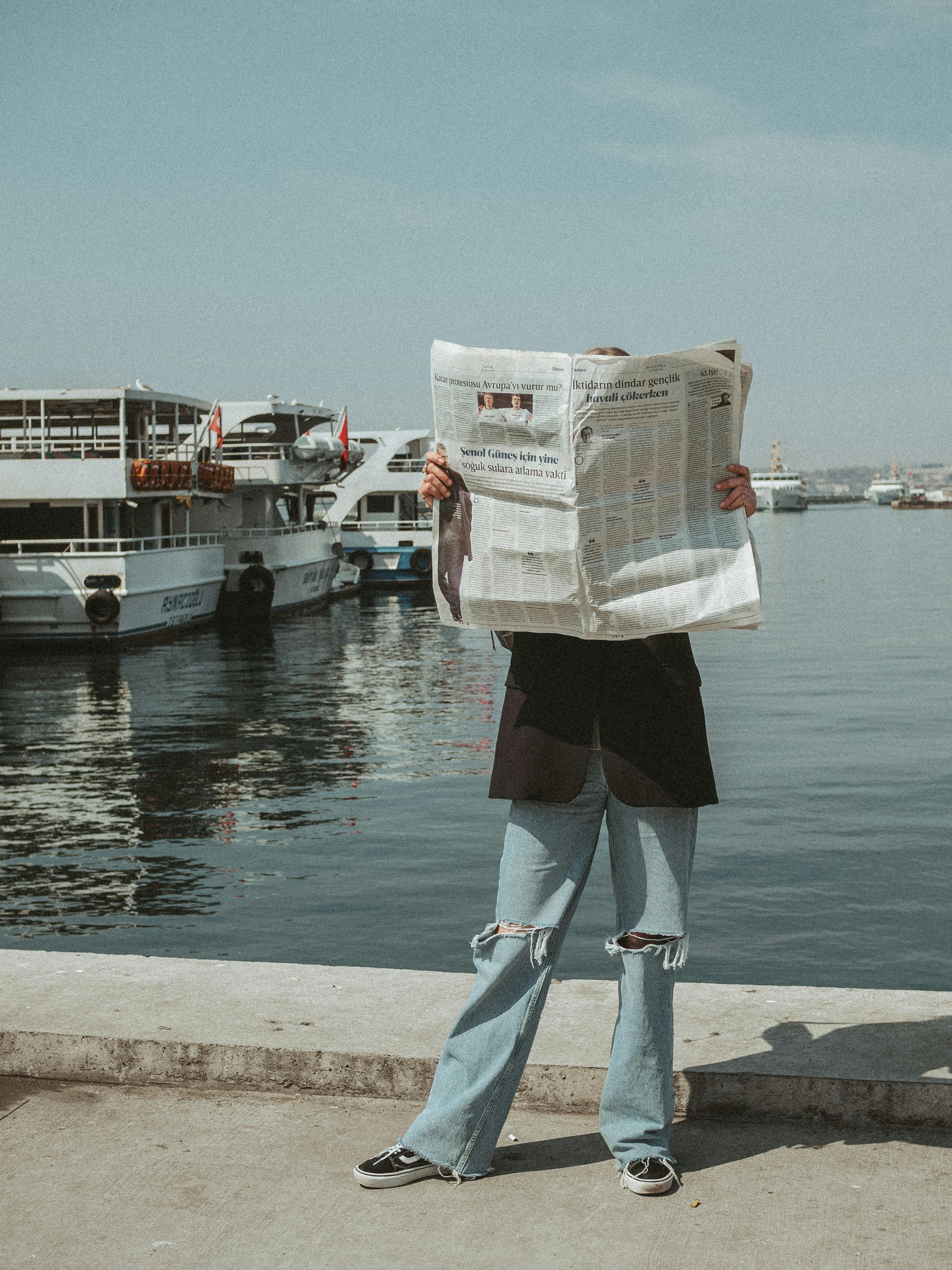 A person reading a newspaper on a sunny day by the waterfront in Istanbul, Turkey.