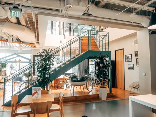 Free Bright modern open office with bicycles, expansive staircase, and plants offering a welcoming workspace environment. Stock Photo