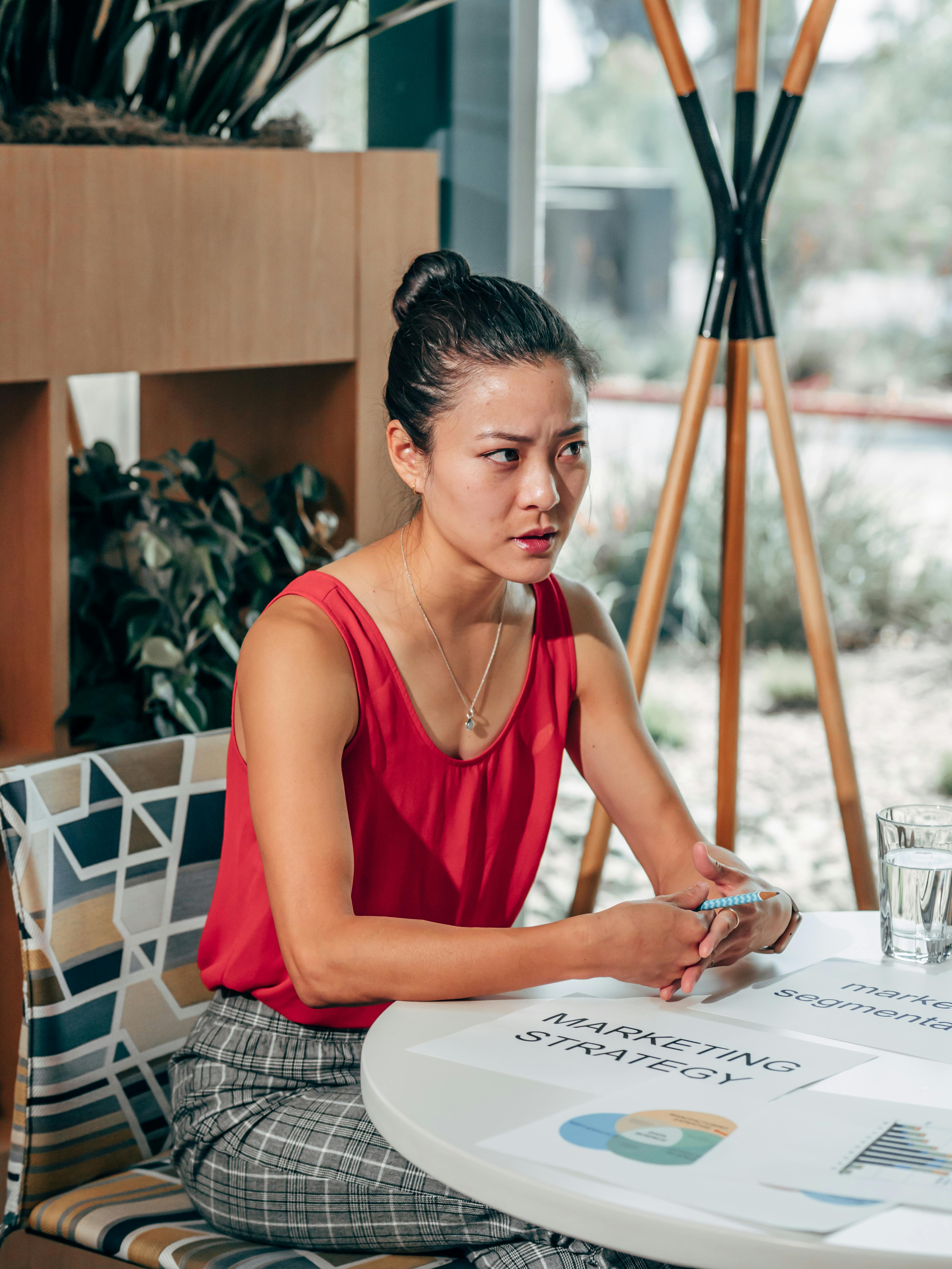 serious asian marketer speaking at desk with papers in office