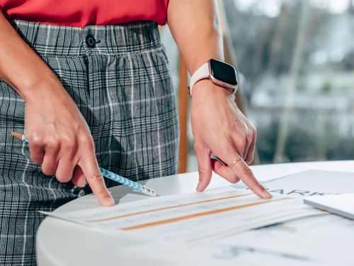 Free Businesswoman examining documents on a desk with a smartwatch and pen. Stock Photo