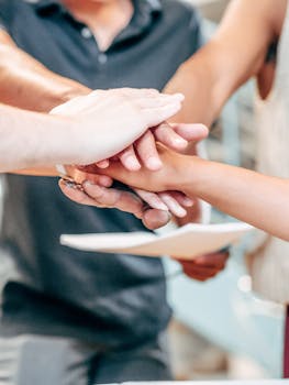 Diverse team members unite hands in a symbol of partnership and success.