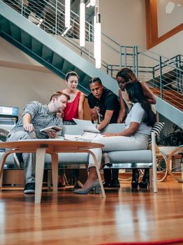 A diverse group of colleagues brainstorming in a modern office space with a staircase backdrop.
