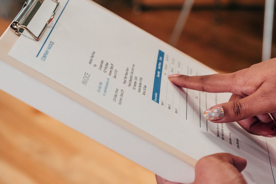 Close-up image of a person pointing to a document on a clipboard, indoors.