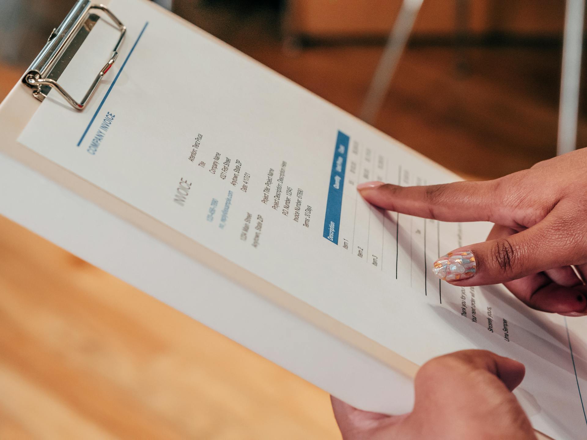 Close-up image of a person pointing to a document on a clipboard, indoors.