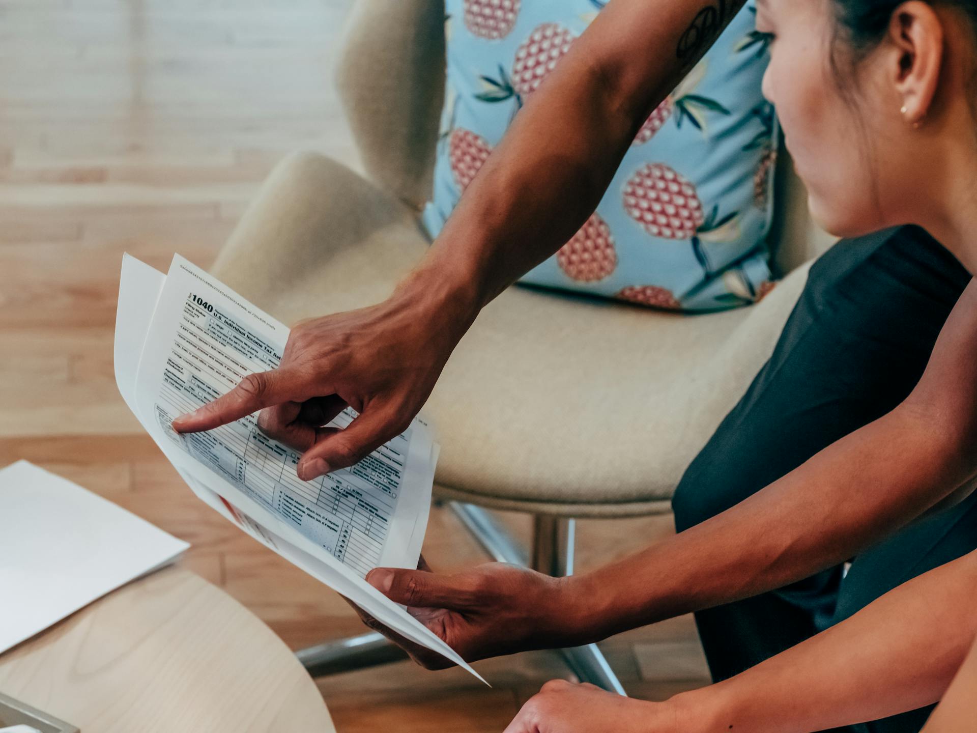 Two individuals examining financial documents closely, focusing on detail.