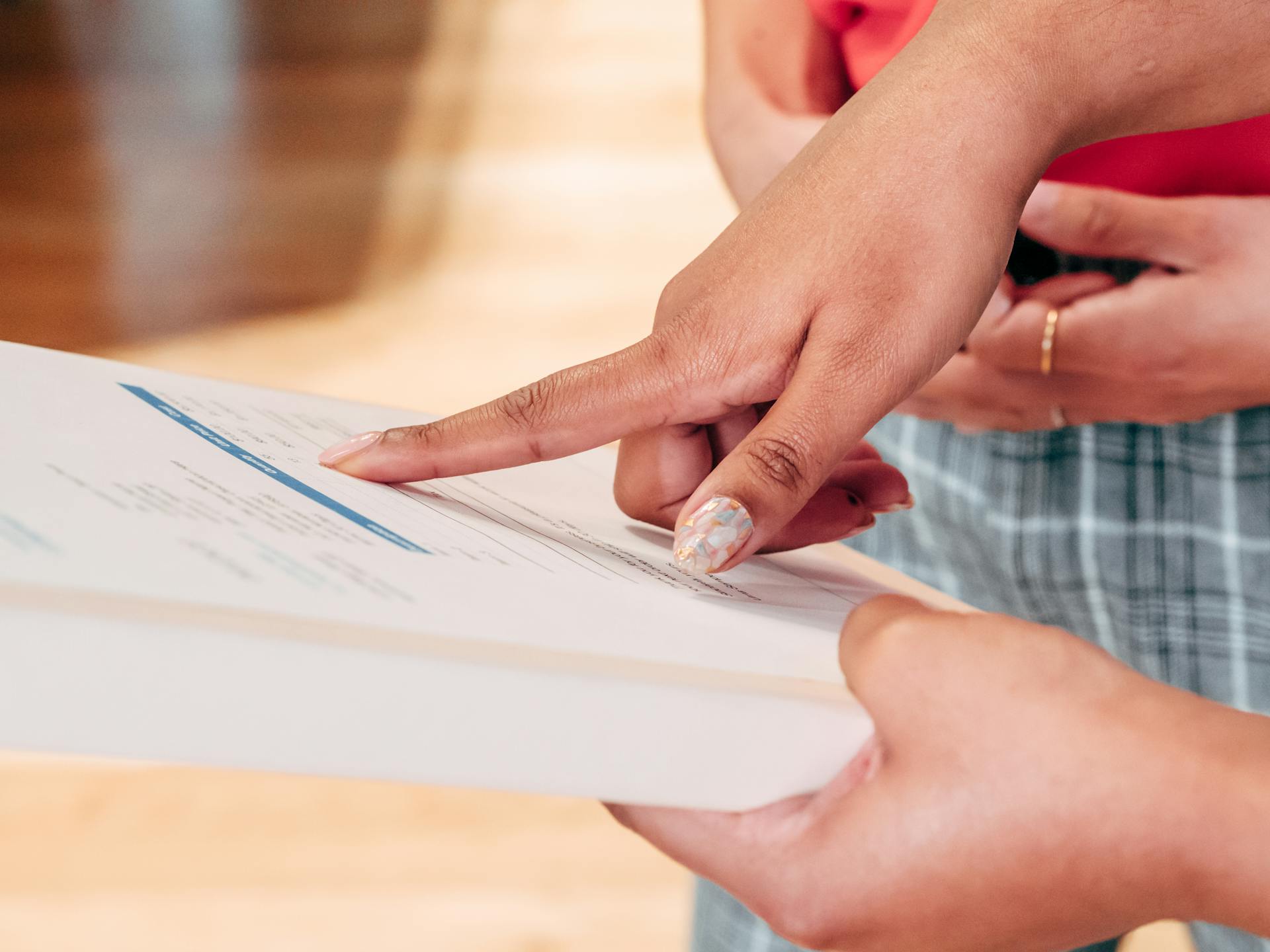 Detailed close-up of hands interacting with a financial document indoors.