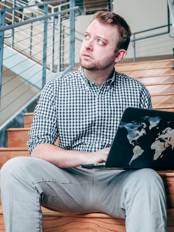 Person smiling and relaxed while working on a laptop in a bright workspace