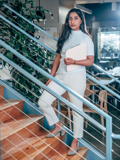 Free Confident businesswoman holding documents on a modern office staircase. Stock Photo