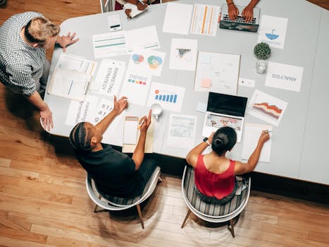 Top view of diverse colleagues in a business meeting discussing strategies with charts and laptops.