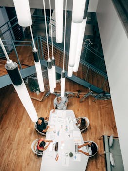Overhead view of colleagues in a meeting room with modern lighting and creative workspace.