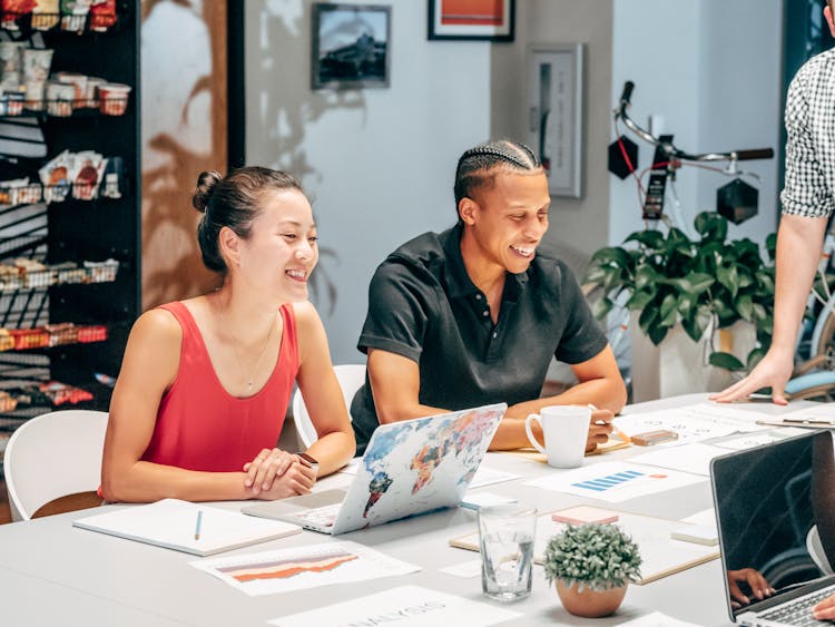 Happy Coworkers Sitting Next To Each Other At An Office