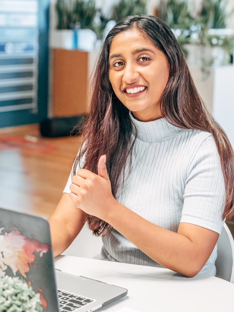 Woman In White Shirt Sitting At Table With Laptop