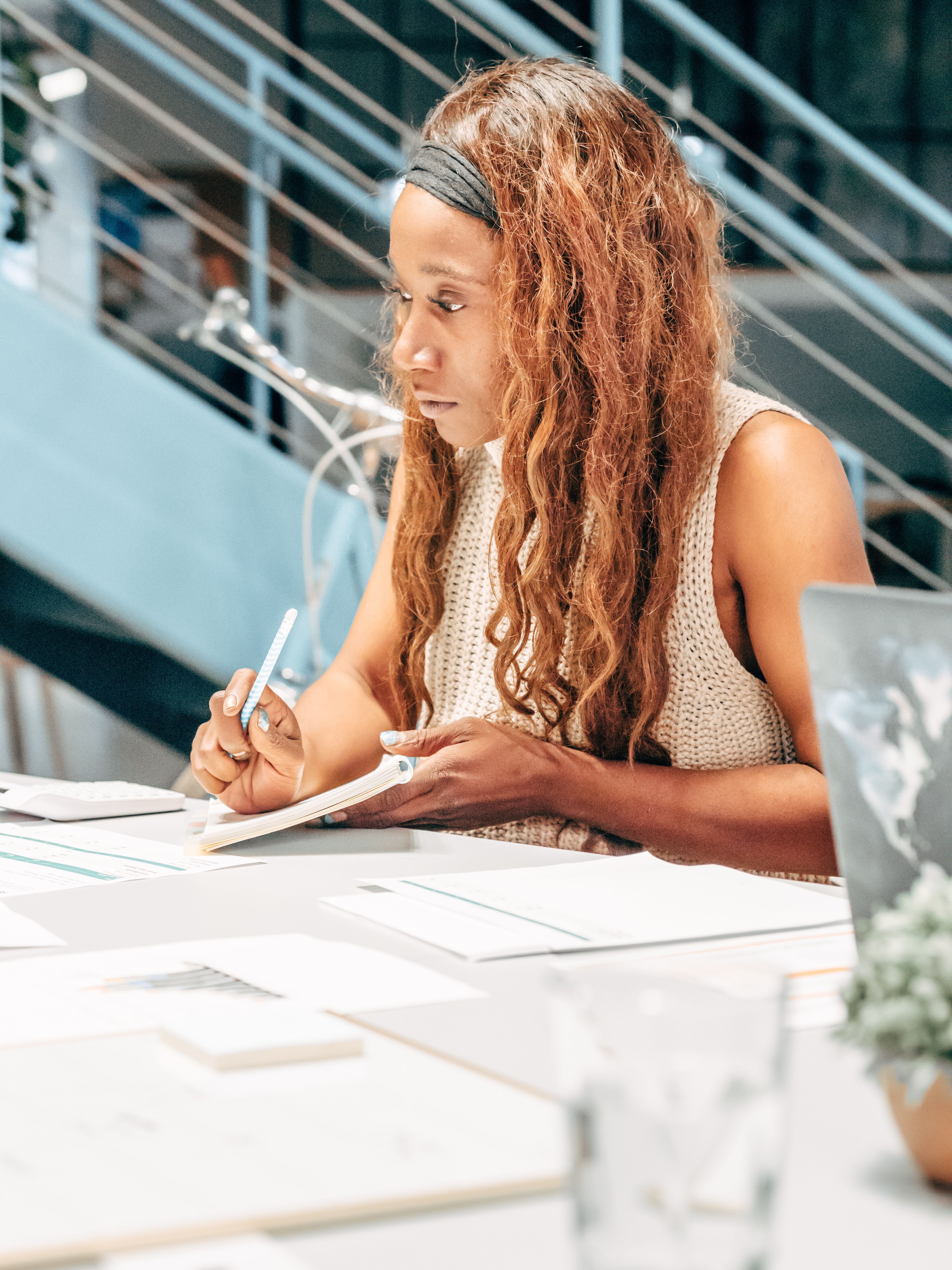 woman working at an office with several stacks of paper laid out on the table