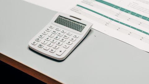 Close-up of a white calculator next to a financial spreadsheet on a desk.