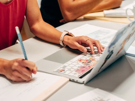 Woman writing notes and using laptop in a modern office setting. Interior workspace scene.