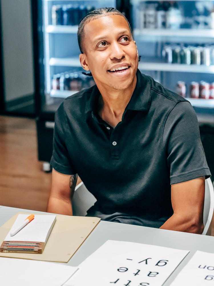 Man In Polo Shirt Sitting At Table Smiling