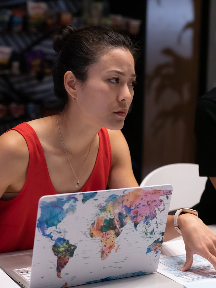 Woman In Red Tank Top Sitting At A Table With Laptop