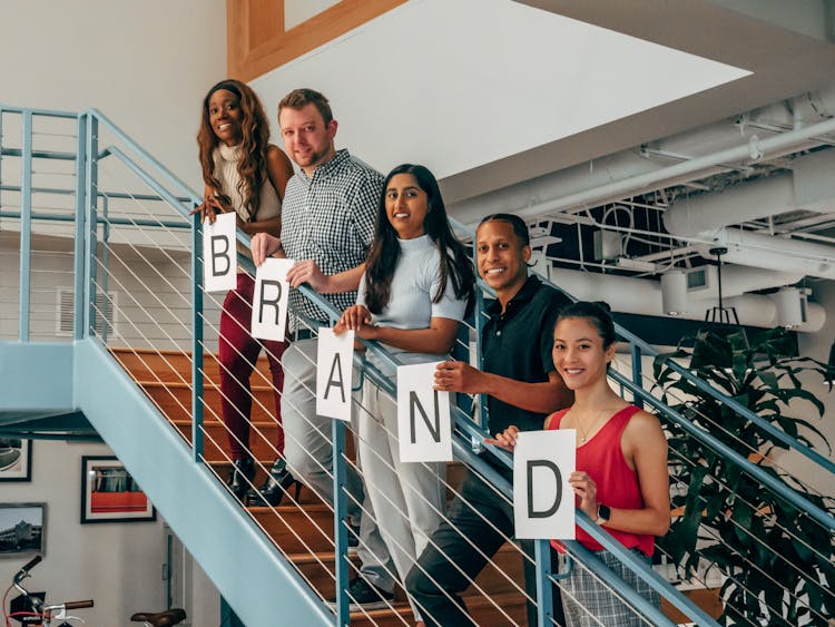 People Holding Paper With Letters While Standing On The Stairs