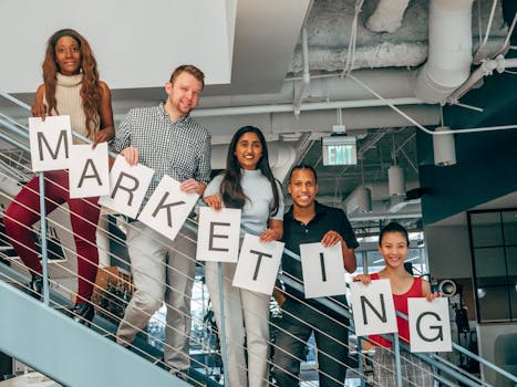 A diverse group of professionals holding a marketing sign in a modern office setting.