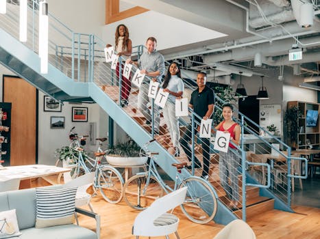 Diverse coworkers holding 'MARKETING' signs on staircase in modern office.