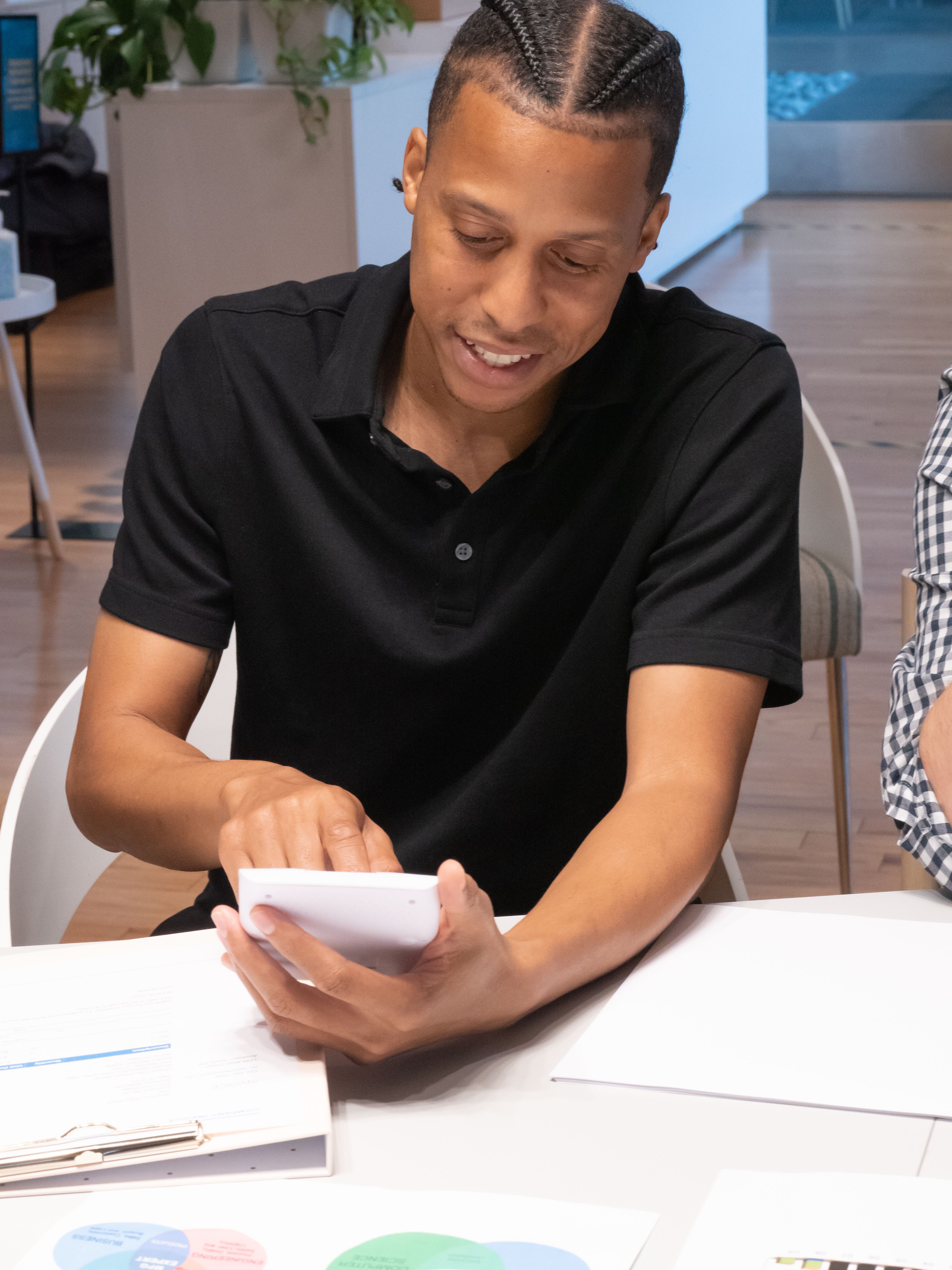 A man in an office setting uses a calculator during a meeting, highlighting teamwork.