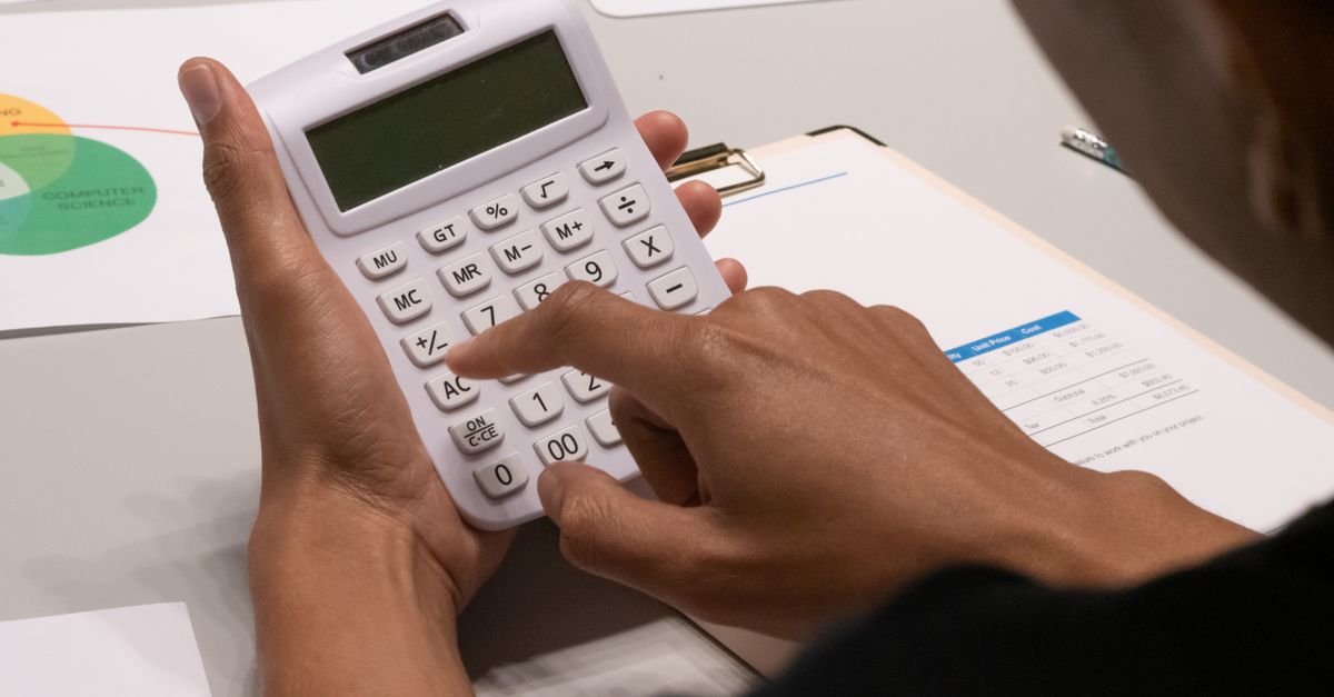 Focused image of a person using a calculator amidst financial documents and charts.