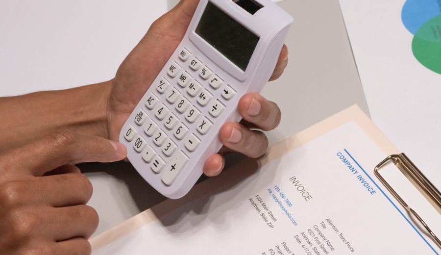 Hands using a calculator beside a printed invoice