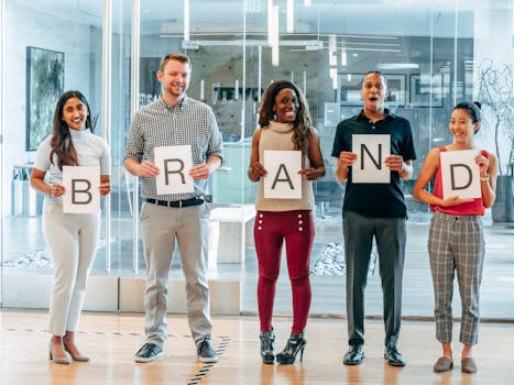 Diverse business team smiling and holding signs spelling 'BRAND' in a modern office.