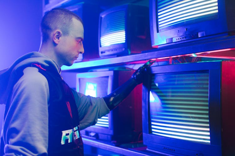 A Man With Prosthetic Hand Holding A TV With Horizontal Static Lines On Screen