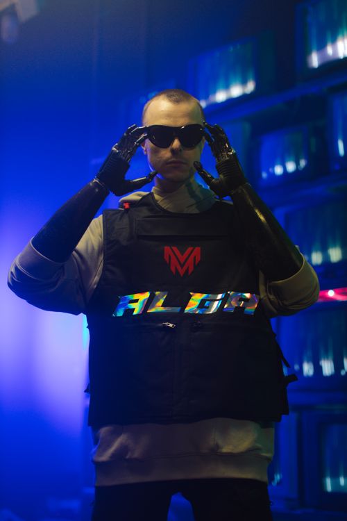 Free A man in a cyberpunk setting wearing sunglasses, prosthetics, and futuristic attire. Stock Photo