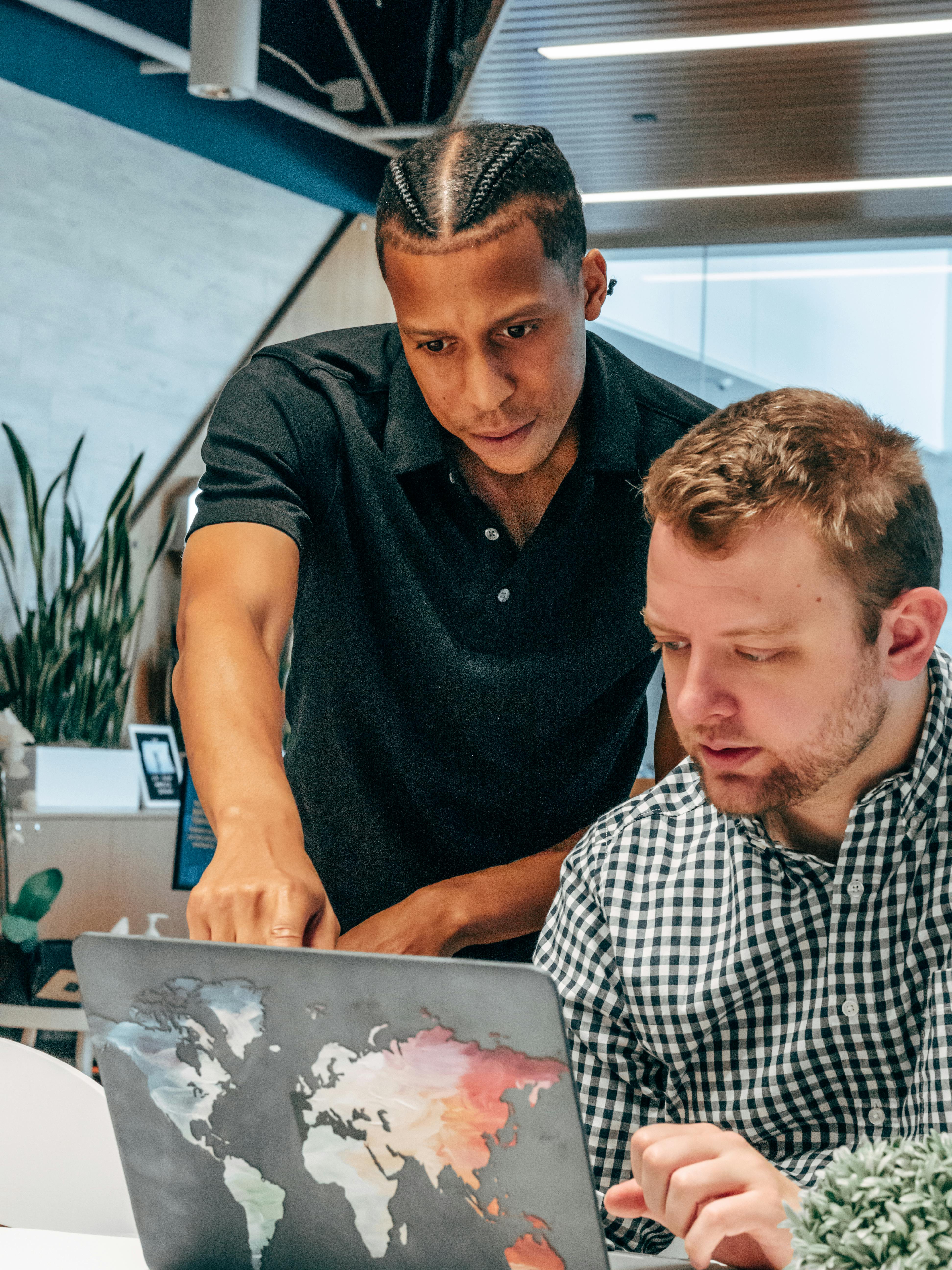 Two diverse colleagues collaborating over a laptop in a modern office environment.