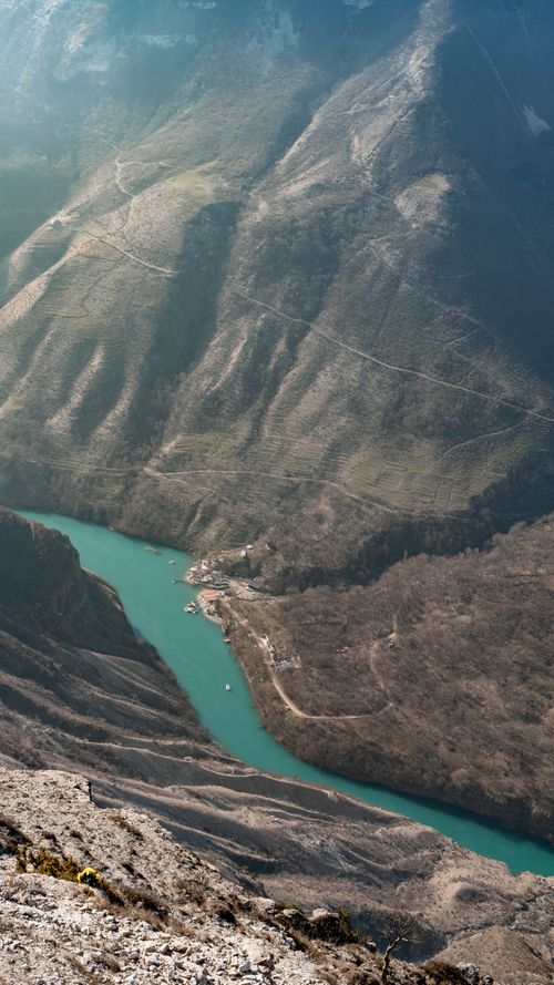 Free A stunning high-angle shot of a winding turquoise river cutting through a rugged mountain valley. Stock Photo