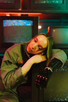 A woman with a prosthetic arm leans on retro TVs in a vibrant, artistic setting.