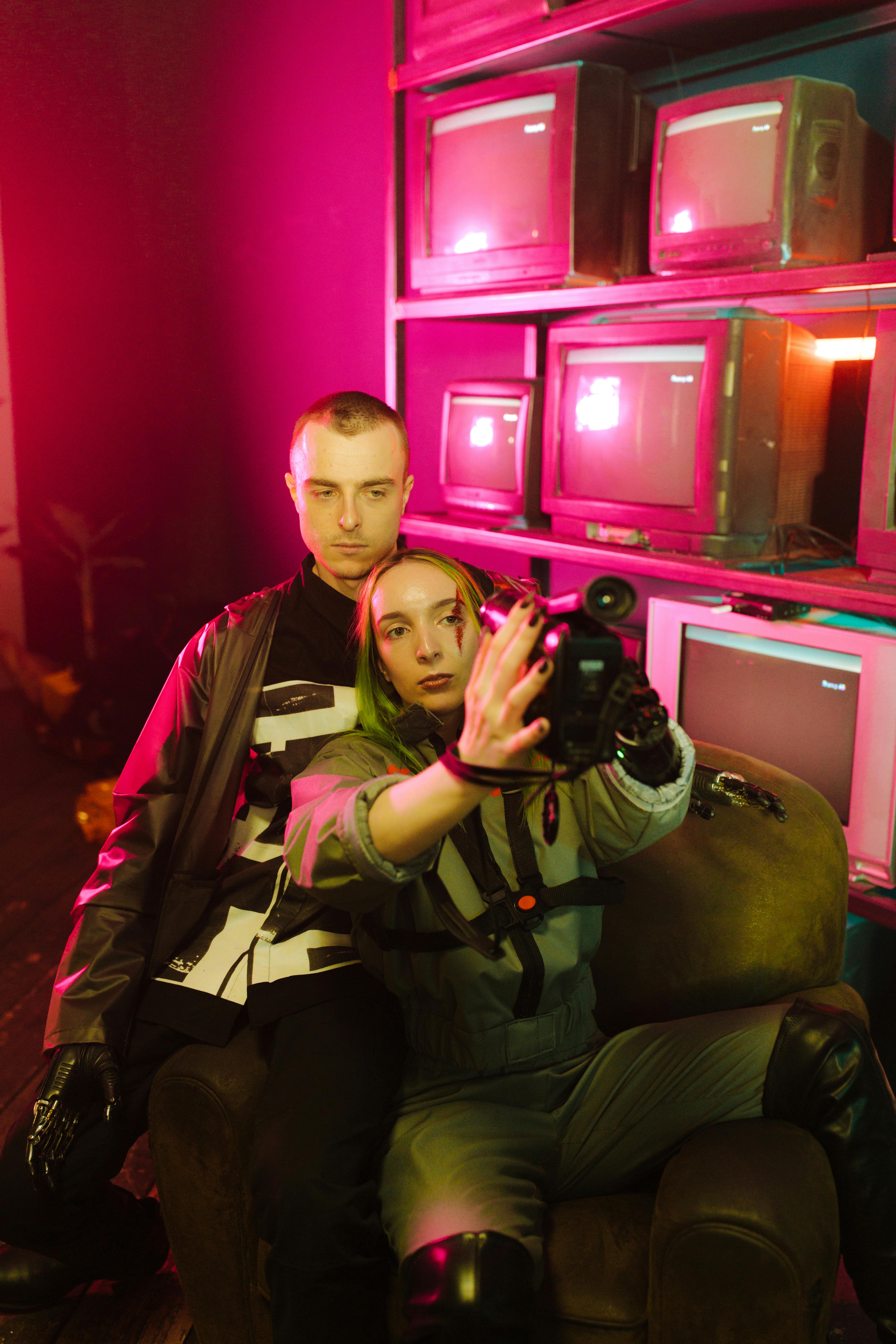 man and woman recording themselves in pink light