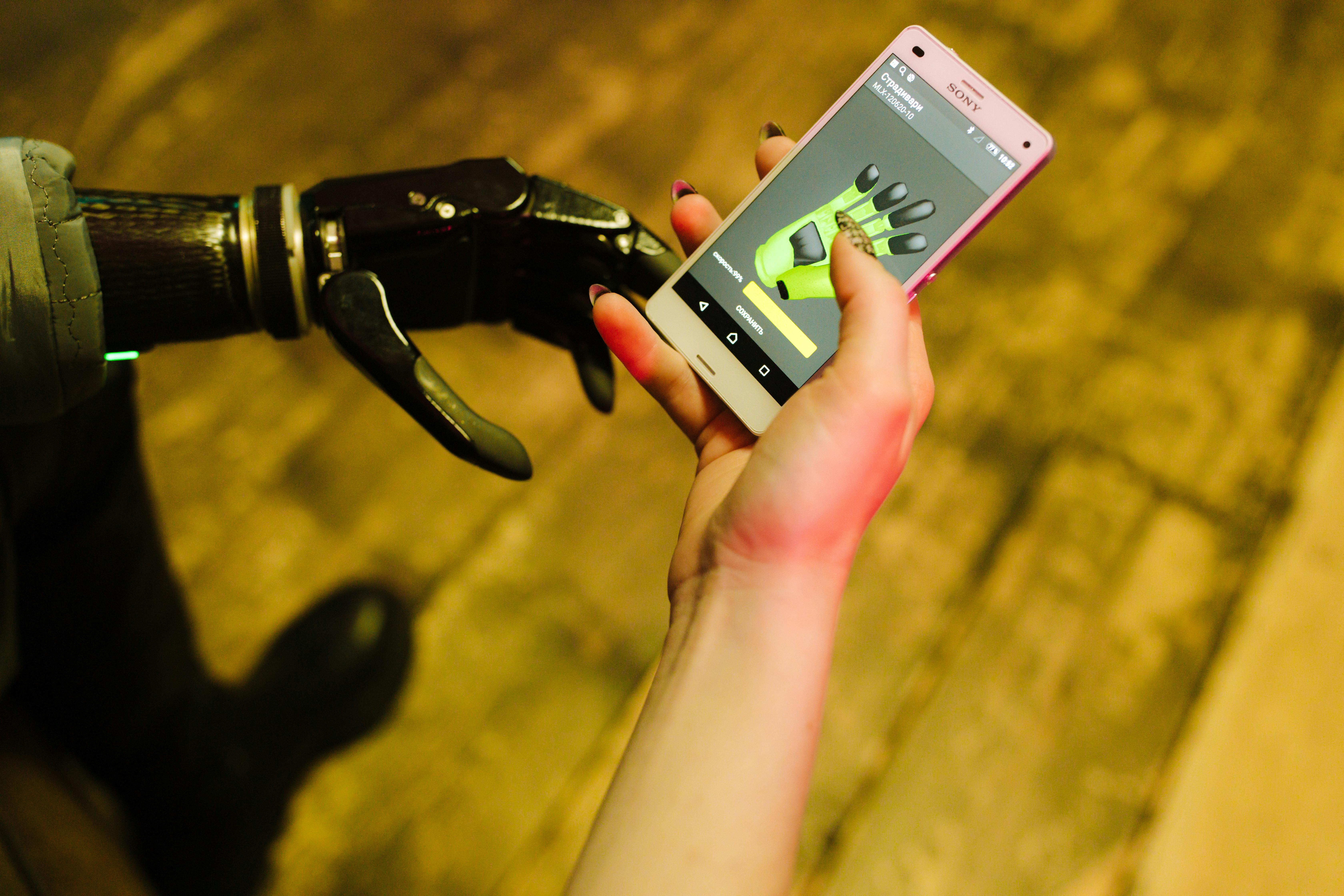 A close-up of a prosthetic hand interacting with a smartphone showcasing futuristic technology.