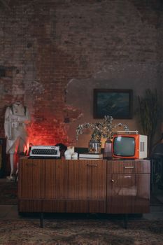 Stylish vintage interior featuring a retro television and typewriter on a wooden cabinet with nostalgic decor.