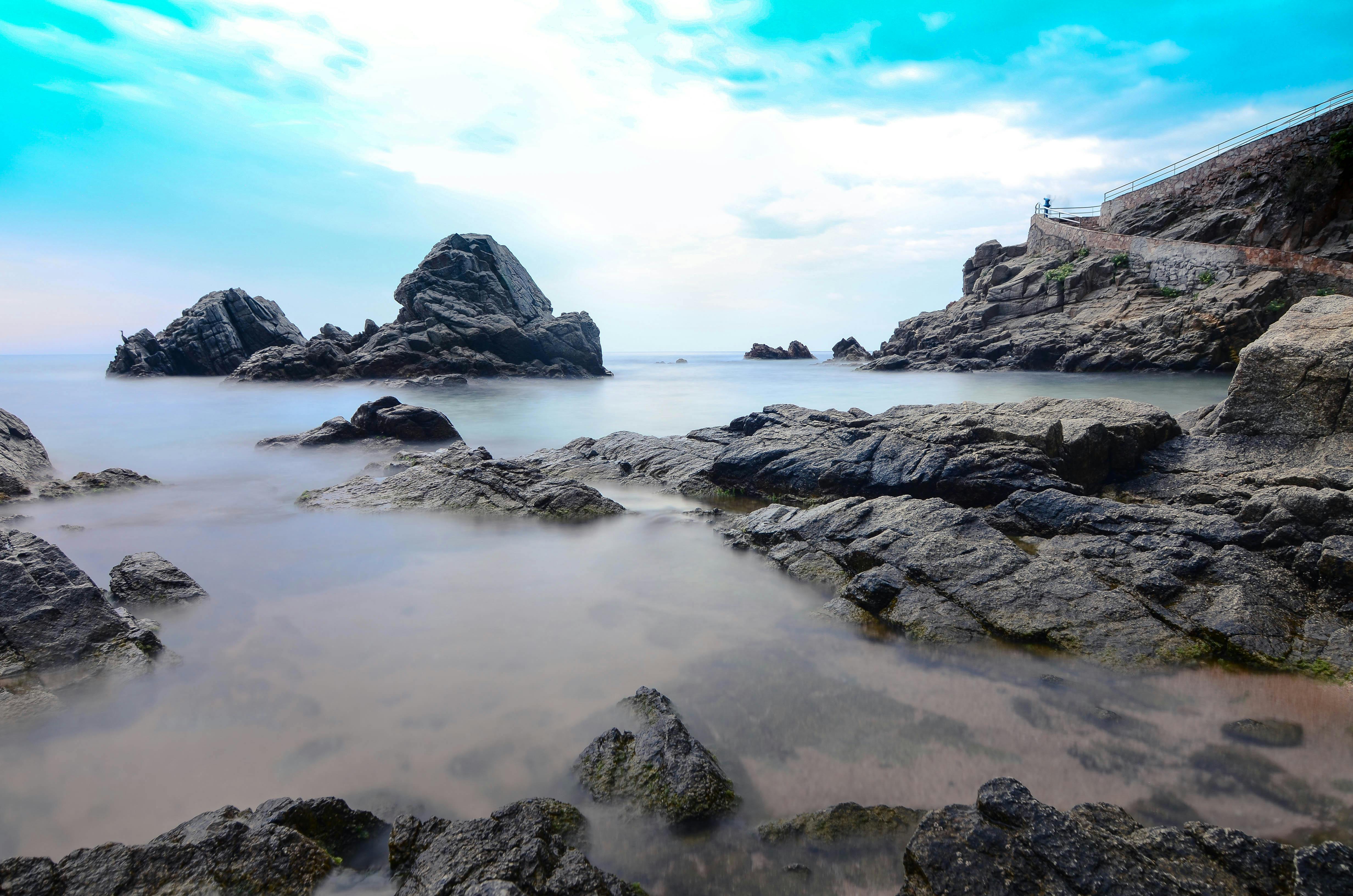Long exposure shot of rocky coastline in Catalonia, Spain, with serene sea and blue sky. - Costa Brava