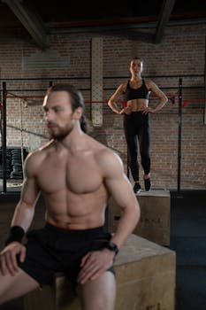 A man and a woman performing fitness activities on plyo boxes in a gym setting.