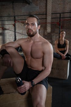 A muscular man and woman taking a break on gym boxes, showcasing fitness and strength.